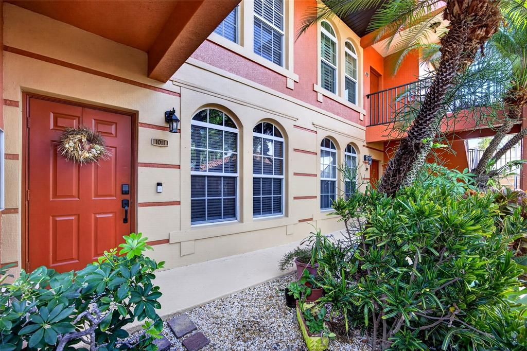 The exterior of a two-story building features a red front door and arched windows — 3500 MONDOVI COURT UNIT 1011, PUNTA GORDA, FL