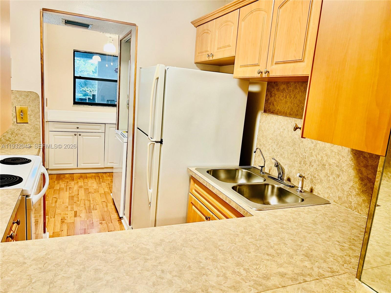 A kitchen features light wood cabinets, a white refrigerator, a double sink, and laminate countertops — 1021 Mockingbird Ln # 215, Plantation FL 33324, PLANTATION, FL