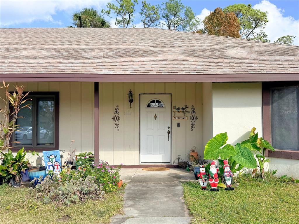 The exterior of a single-story house features a white front door, landscaping, and holiday decorations — 1627 DECATUR AVENUE, HOLLY HILL, FL