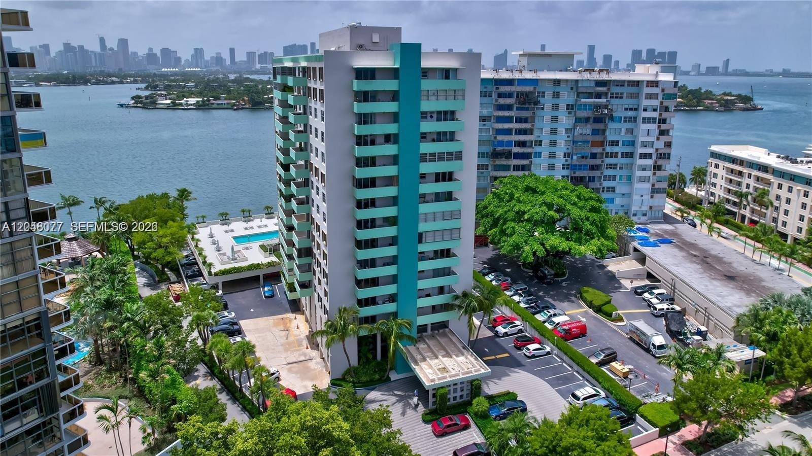 An aerial view shows a tall apartment building with teal balconies next to a parking lot — 5 Island Ave # 8H, Miami Beach FL 33139, MIAMI BEACH, FL