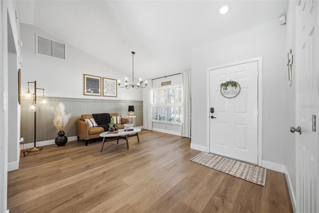A bright entryway features wood-look flooring, a leather sofa, and a white front door — 2409 ARBORWOOD DRIVE, VALRICO, FL