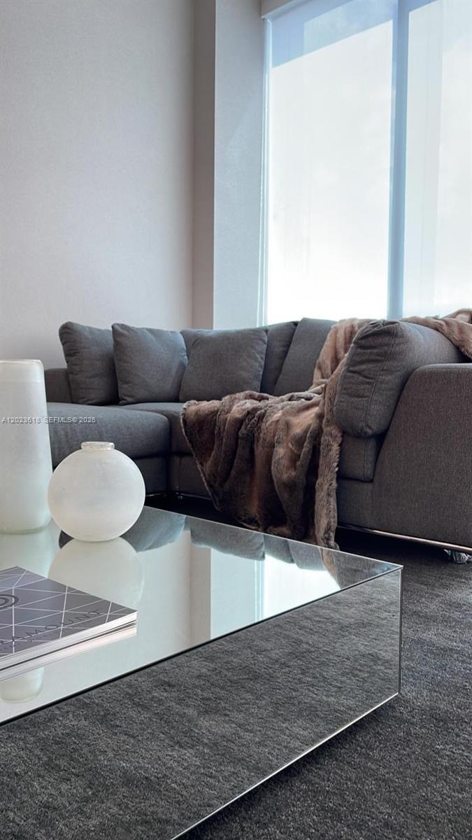 A gray sectional sofa sits in a living room with a mirrored coffee table — 851 NE 1st Ave # 1006, Miami FL 33132, MIAMI, FL
