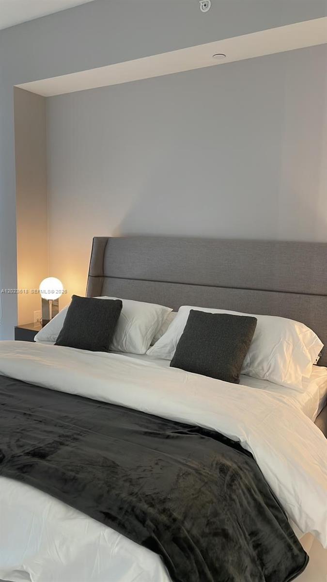 A bedroom features a gray upholstered headboard, white bedding, and a dark throw blanket — 851 NE 1st Ave # 1006, Miami FL 33132, MIAMI, FL