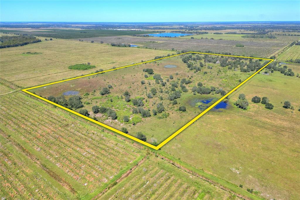 An aerial view shows a large, rectangular plot of grassy land outlined in yellow — 46891 FARABEE ROAD, PUNTA GORDA, FL