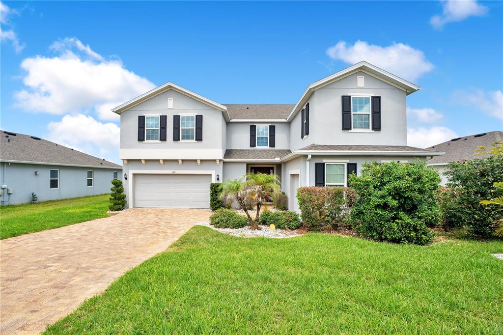 A two-story house with a light gray exterior, a two-car garage, and a paved driveway — 1321 WILDCAT LANE, MINNEOLA, FL