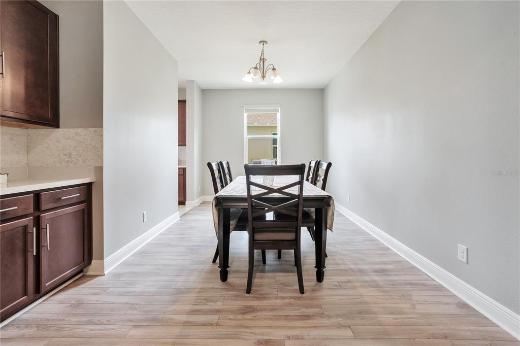 A dining room features wood-look flooring, a dark wood table with chairs, and a window — 1321 WILDCAT LANE, MINNEOLA, FL