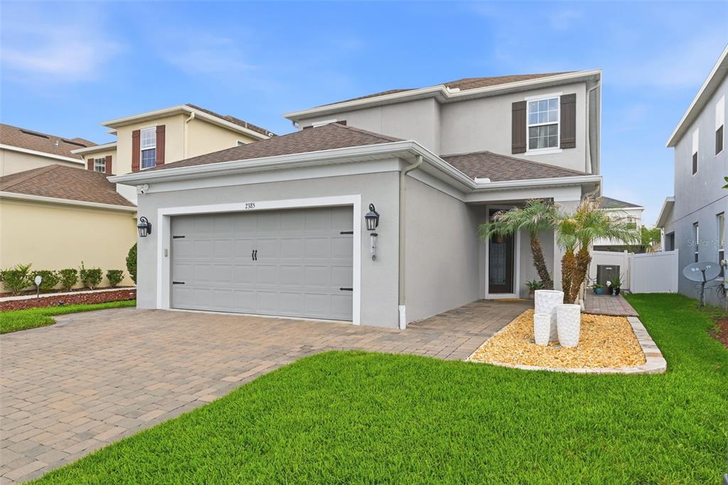 A two-story gray house with a paved driveway, a garage, and a small front garden — 2385 DAMMAR STREET, ORLANDO, FL