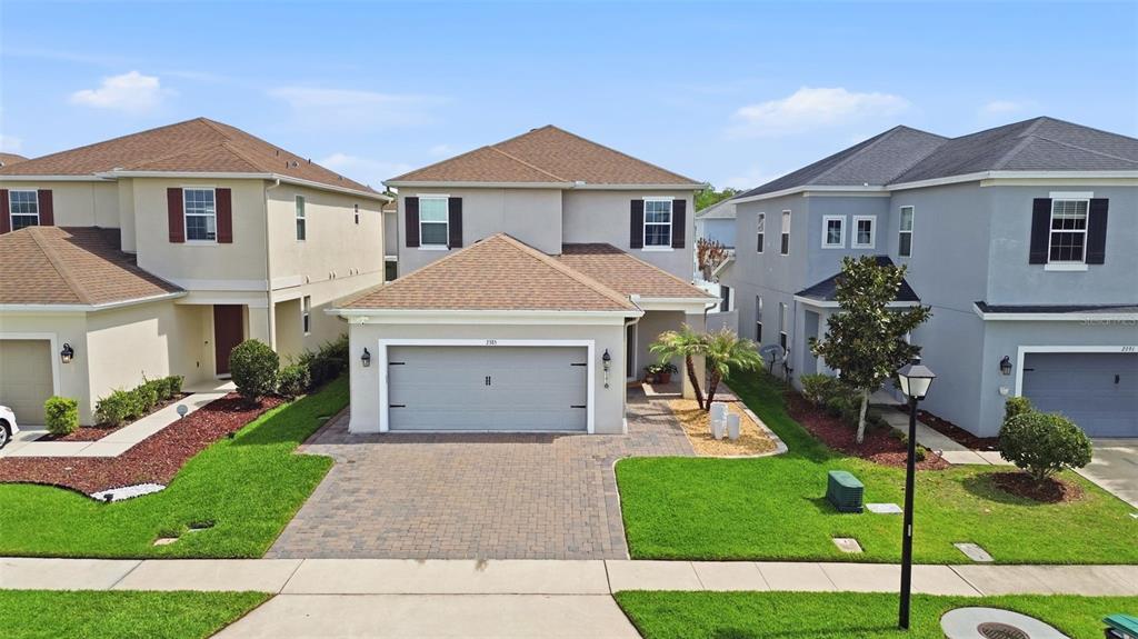 An exterior view of a two-story suburban house with a gray garage and paved driveway — 2385 DAMMAR STREET, ORLANDO, FL