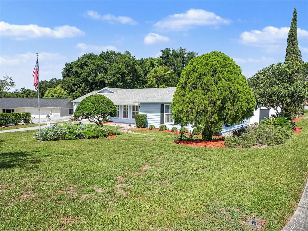 A light blue single-story house with a large front lawn and mature landscaping — 7207 IMMOKALEE COURT, ORLANDO, FL