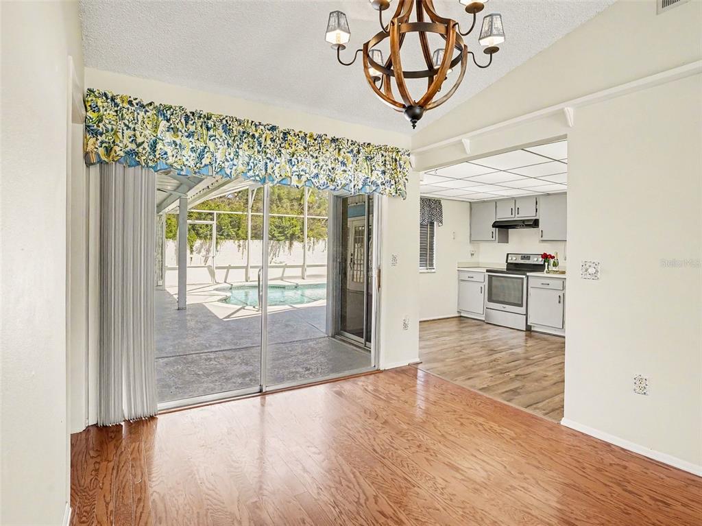 A dining area with wood flooring leads to a kitchen and a sliding glass door — 7207 IMMOKALEE COURT, ORLANDO, FL
