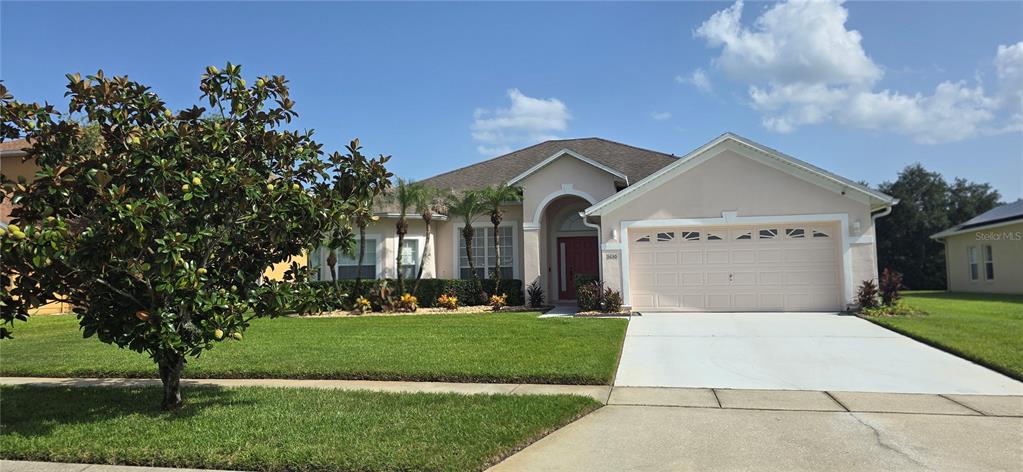 A single-story house with a beige exterior, a two-car garage, and a large front lawn — 3630 KARIBA COURT, KISSIMMEE, FL