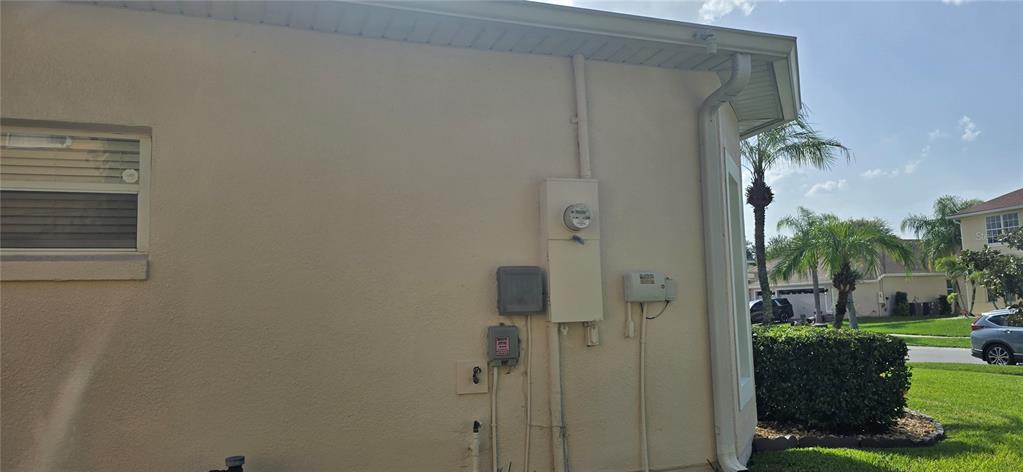 The exterior side wall of a house features an electrical meter and utility boxes — 3630 KARIBA COURT, KISSIMMEE, FL
