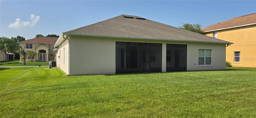 The exterior rear view of a single-story house features a screened-in porch and lawn — 3630 KARIBA COURT, KISSIMMEE, FL