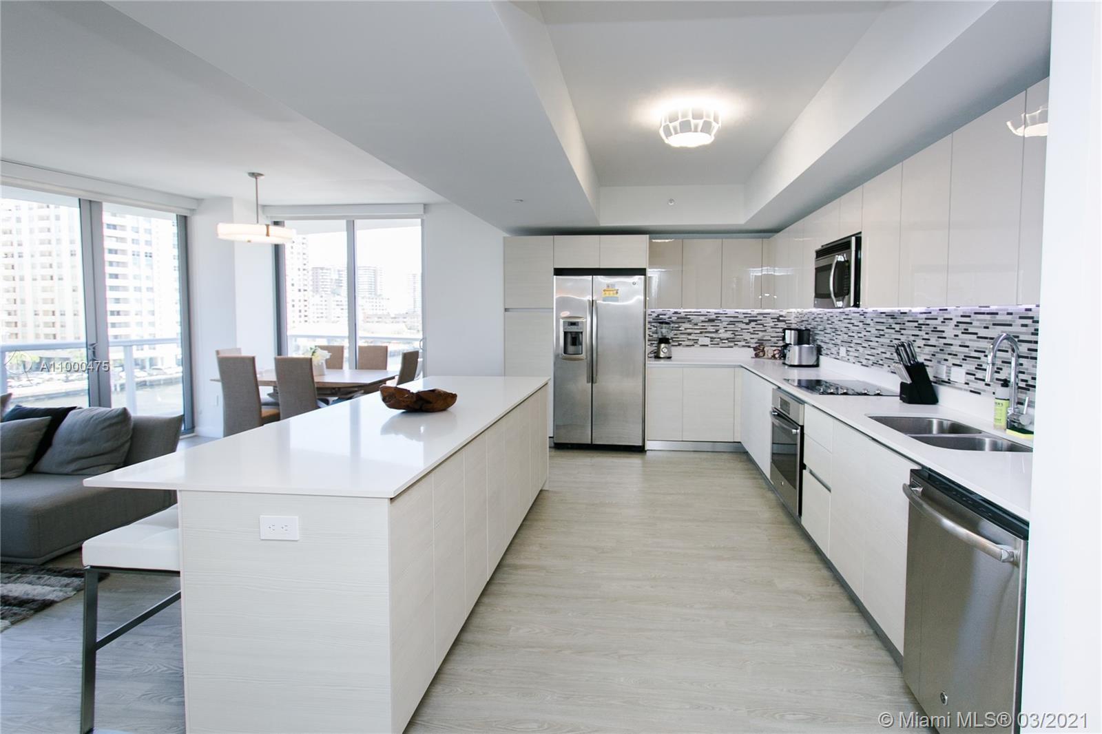 A modern kitchen features white cabinetry, stainless steel appliances, and a large central island — 2600 E Hallandale Beach Blvd, Hallandale Beach FL 33009, HALLANDALE BEACH, FL