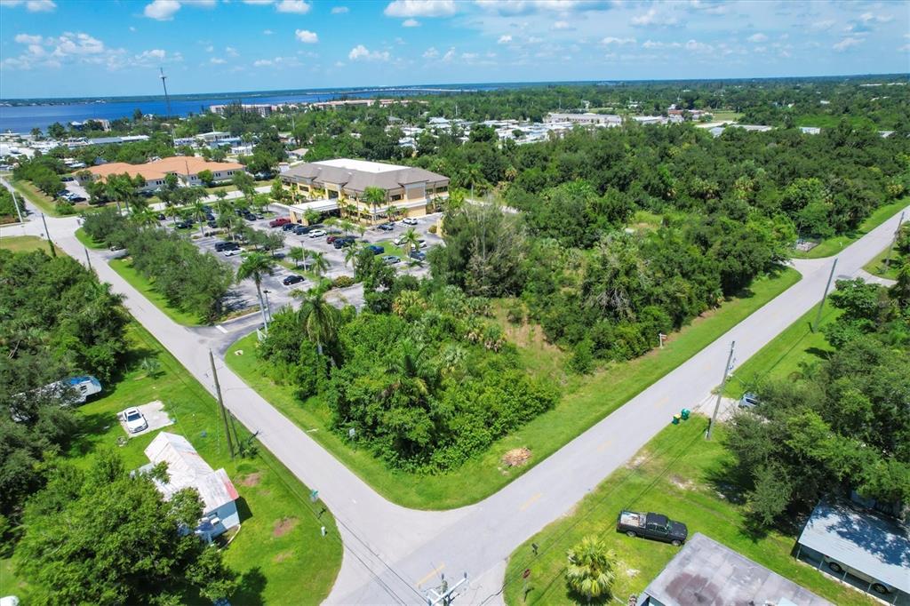 An aerial view shows a vacant wooded lot situated between two roads and a commercial building — 1010 LAVILLA ROAD, PUNTA GORDA, FL
