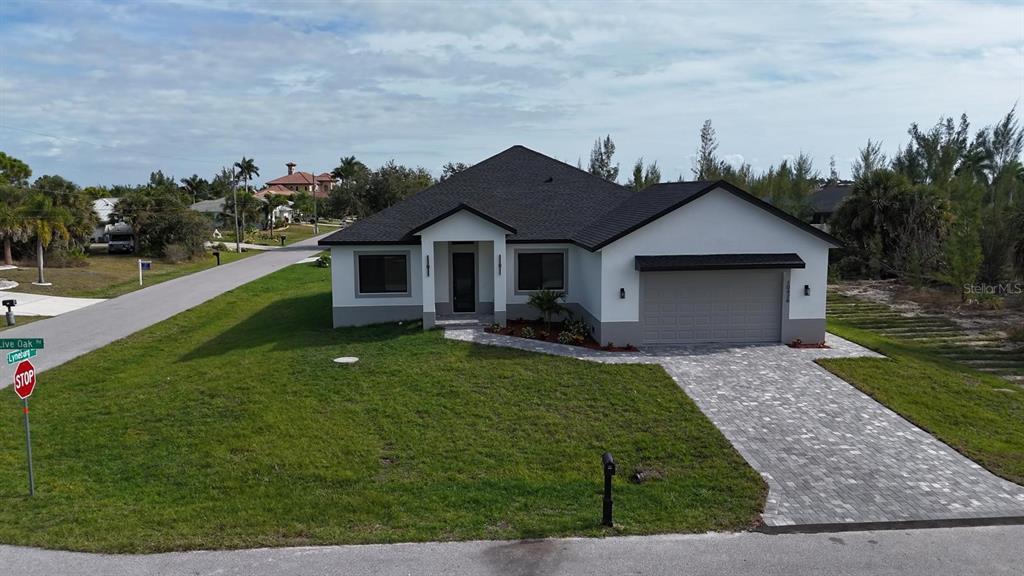 A single-story house with a white exterior, dark roof, and a paved driveway — 10426 LIVE OAK ROAD, PORT CHARLOTTE, FL
