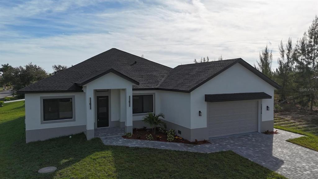 A single-story house with a white exterior, dark roof, and a paved driveway — 10426 LIVE OAK ROAD, PORT CHARLOTTE, FL