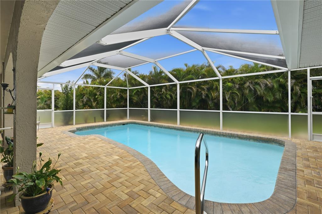 A screened-in swimming pool with a paver deck and lush green privacy landscaping — 25378 RUPERT ROAD, PUNTA GORDA, FL