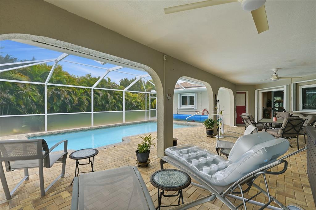 A covered patio features brick pavers, outdoor furniture, and a screened-in swimming pool — 25378 RUPERT ROAD, PUNTA GORDA, FL