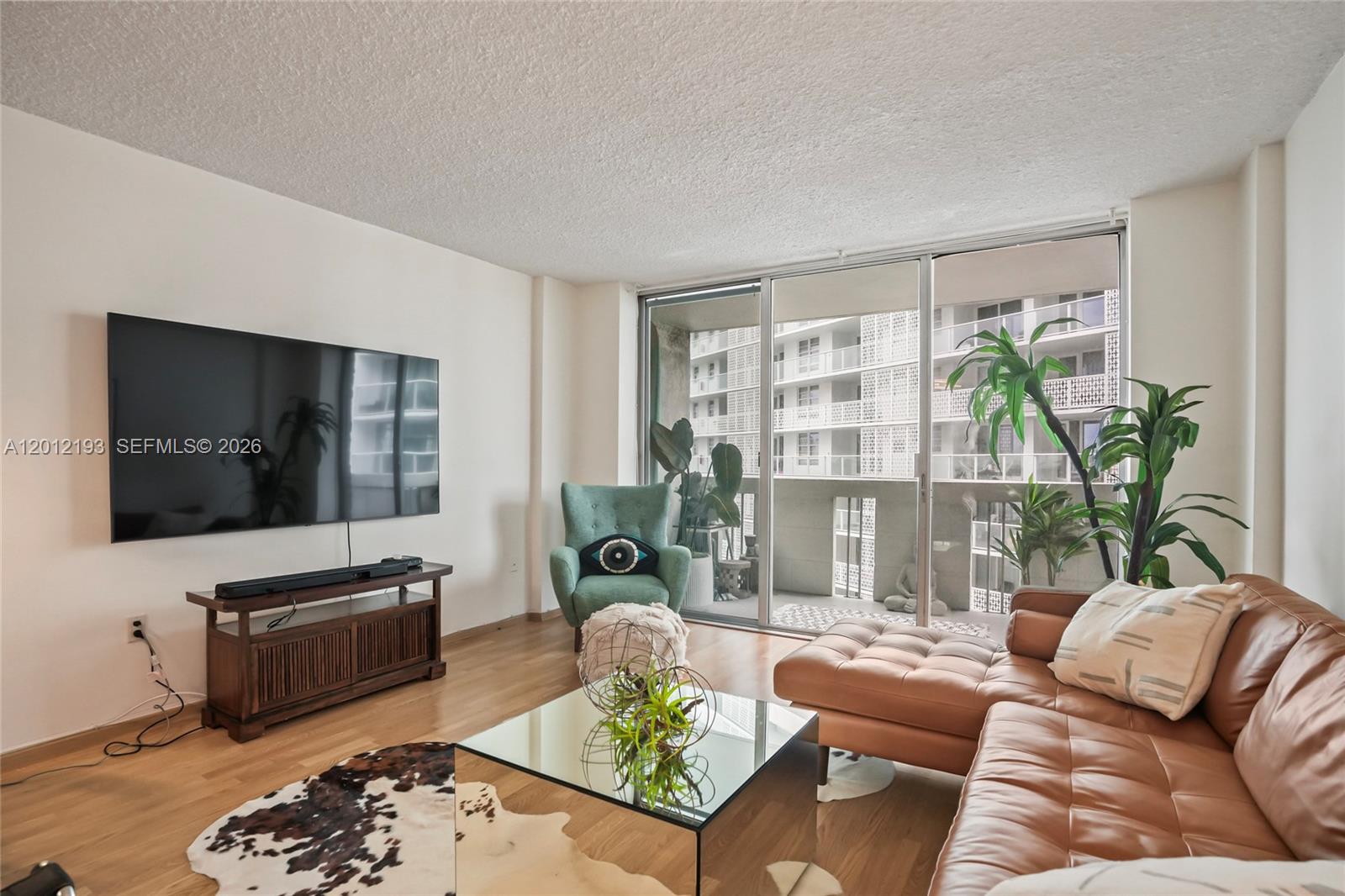 A living room features a brown leather sectional, a teal armchair, and a glass coffee table — 800 West Ave # 738, Miami Beach FL 33139, MIAMI BEACH, FL