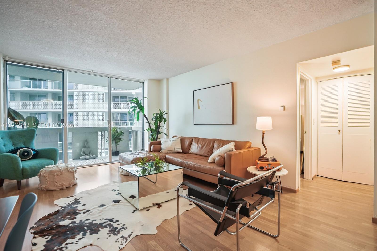 A living room features a leather sofa, a mirrored coffee table, and a balcony view — 800 West Ave # 738, Miami Beach FL 33139, MIAMI BEACH, FL