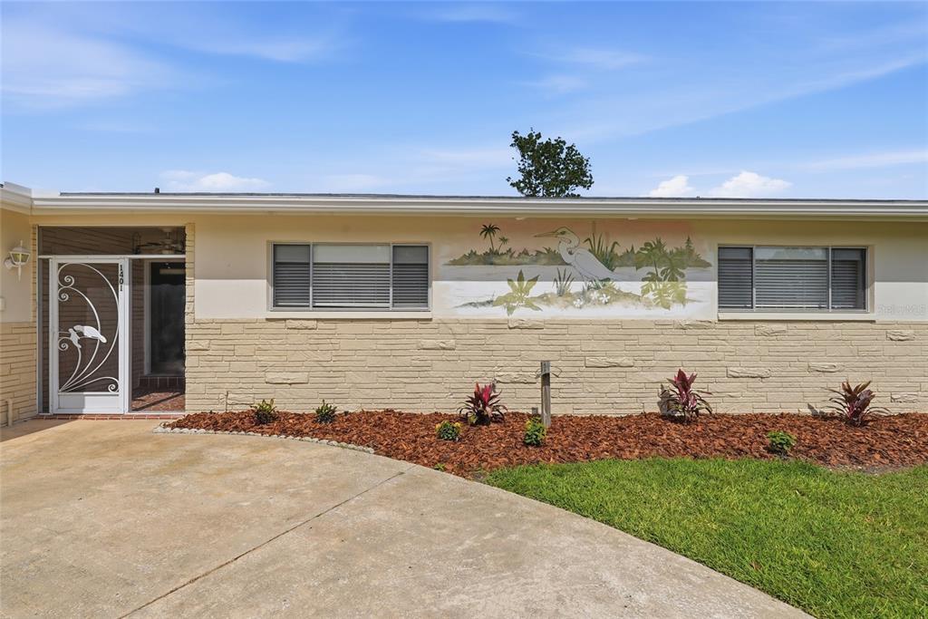 The exterior of a single-story house features a painted mural, stone siding, and a driveway — 1401 SE PARADISE AVENUE, CRYSTAL RIVER, FL