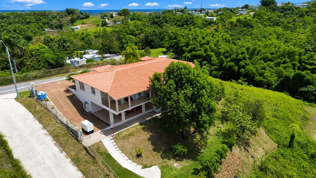 An aerial view shows a two-story house with a red tile roof and surrounding greenery — Car 416 km 2.3 PIEDRAS BLANCAS, AGUADA, PR