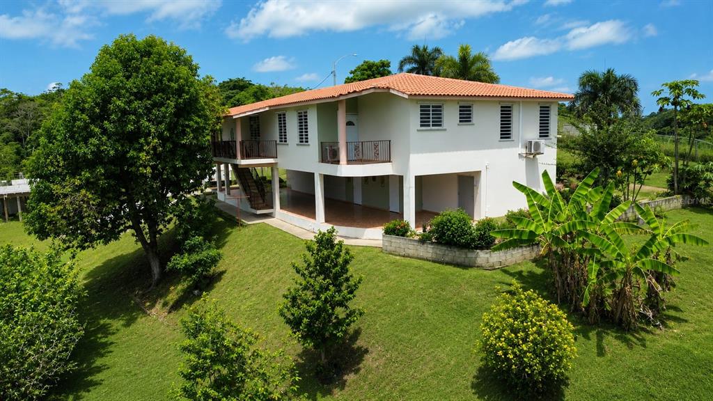 A two-story house with a tiled roof, an open ground level, and a grassy yard — Car 416 km 2.3 PIEDRAS BLANCAS, AGUADA, PR