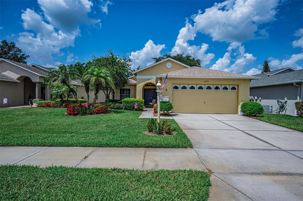A single-story house with a yellow exterior, a two-car garage, and a manicured front lawn — 1323 WINDING WILLOW DRIVE, TRINITY, FL