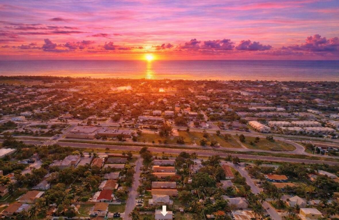 An aerial view of a coastal neighborhood at sunset with a white arrow pointing downward — 250 NE 13th Street, Delray Beach FL 33444, DELRAY BEACH, FL