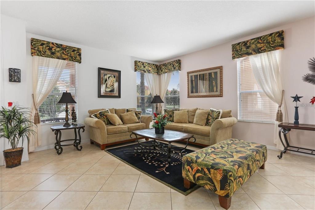 A living room features beige tile floors, two tan sofas, and tropical-patterned window valances — 4515 STELLA STREET, KISSIMMEE, FL