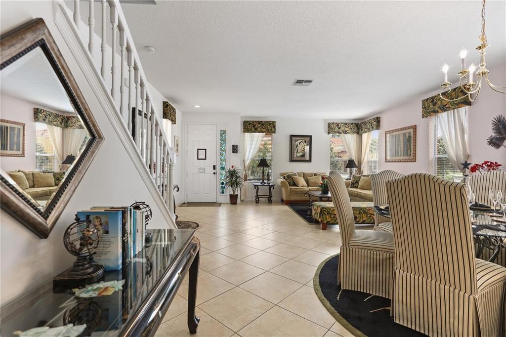 An open-concept living and dining area features tile flooring, a staircase, and a chandelier — 4515 STELLA STREET, KISSIMMEE, FL