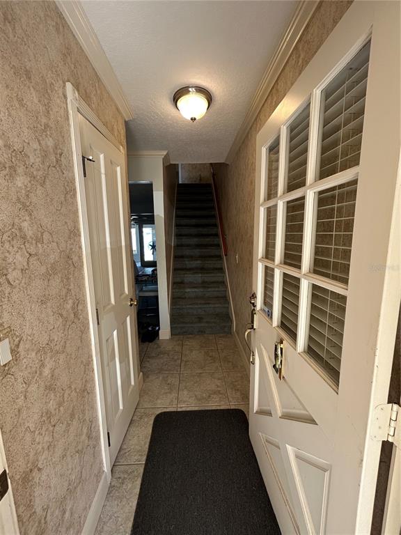 An entryway features a tiled floor, a staircase, a white door, and patterned wallpaper — 11001 SE SUNSET HARBOR ROAD UNIT A04, SUMMERFIELD, FL
