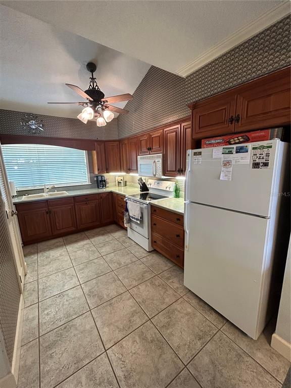 A kitchen features wood cabinets, a white refrigerator, a stove, and patterned wallpaper — 11001 SE SUNSET HARBOR ROAD UNIT A04, SUMMERFIELD, FL