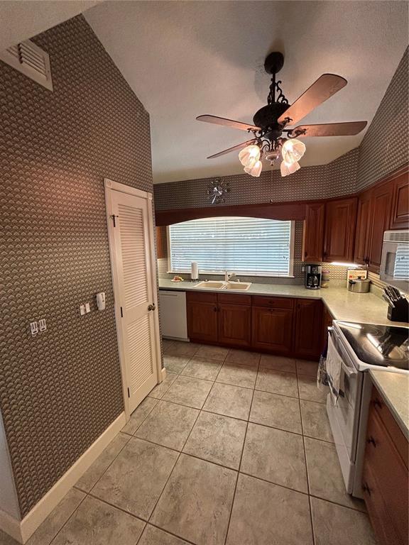 A kitchen features wood cabinets, patterned wallpaper, tile flooring, and a ceiling fan — 11001 SE SUNSET HARBOR ROAD UNIT A04, SUMMERFIELD, FL
