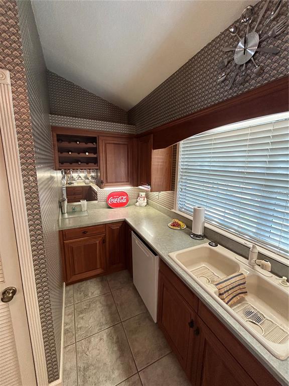 A kitchen features wood cabinets, patterned wallpaper, a sink, and a utensil-themed wall clock — 11001 SE SUNSET HARBOR ROAD UNIT A04, SUMMERFIELD, FL