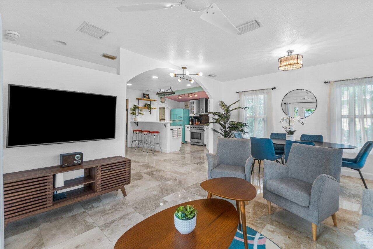 An open-concept living and dining area features tile flooring, a television, and a kitchen — 1911 Parker Avenue, West Palm Beach FL 33401, WEST PALM BEACH, FL