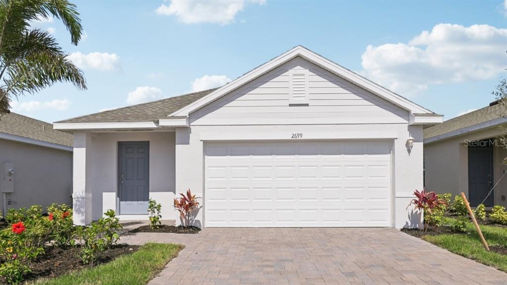 A single-story house with a white stucco exterior, a two-car garage, and a paved driveway — 1469 HARMON DRIVE, PORT CHARLOTTE, FL