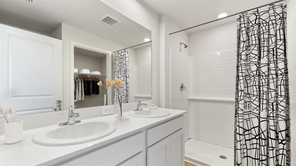 A bathroom features a double vanity with white countertops and a walk-in shower — 1469 HARMON DRIVE, PORT CHARLOTTE, FL