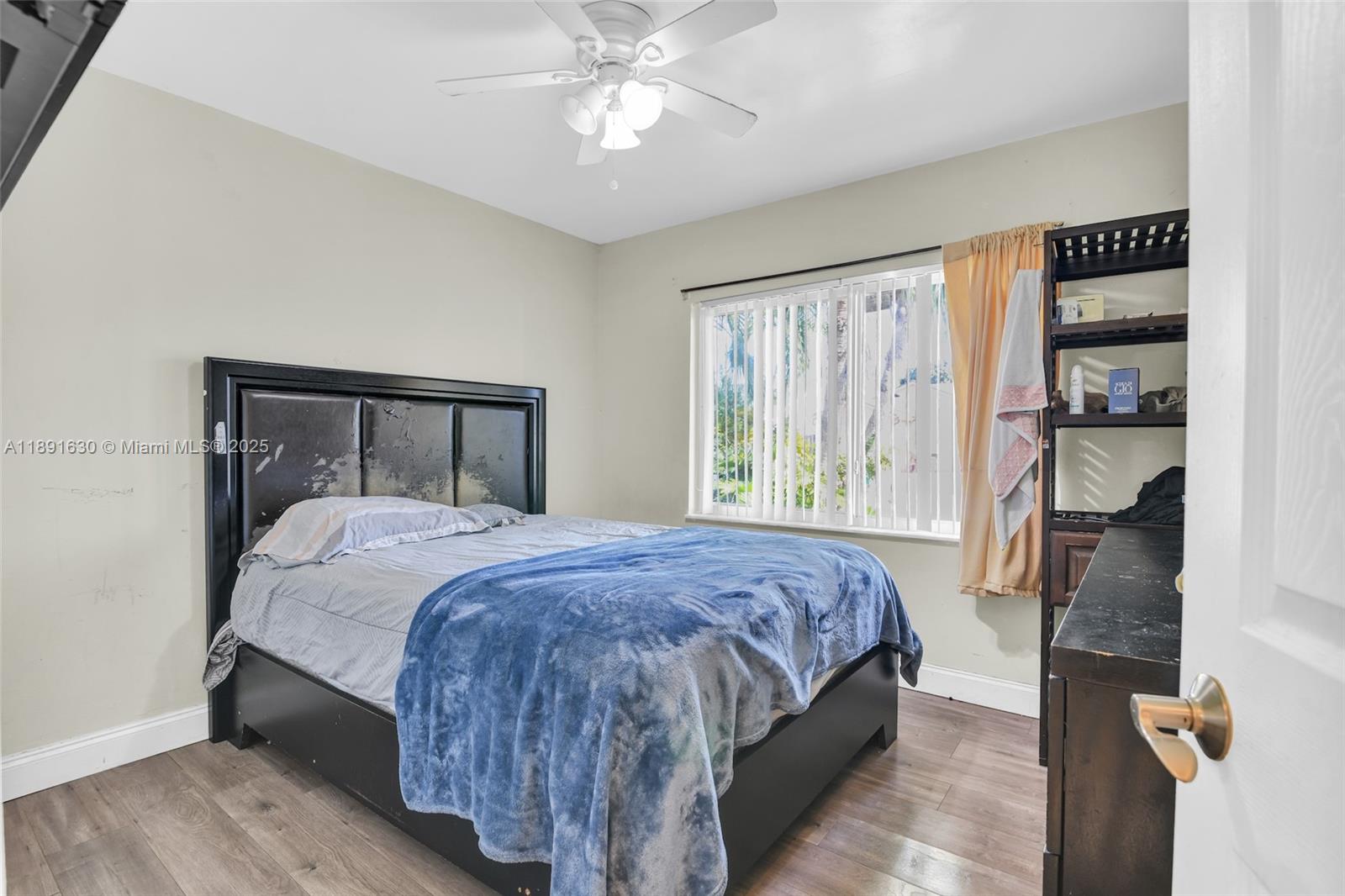 A bedroom features a black bed frame, wood-look flooring, a ceiling fan, and vertical blinds — 13520 SW 116th Ct, Miami FL 33176, MIAMI, FL