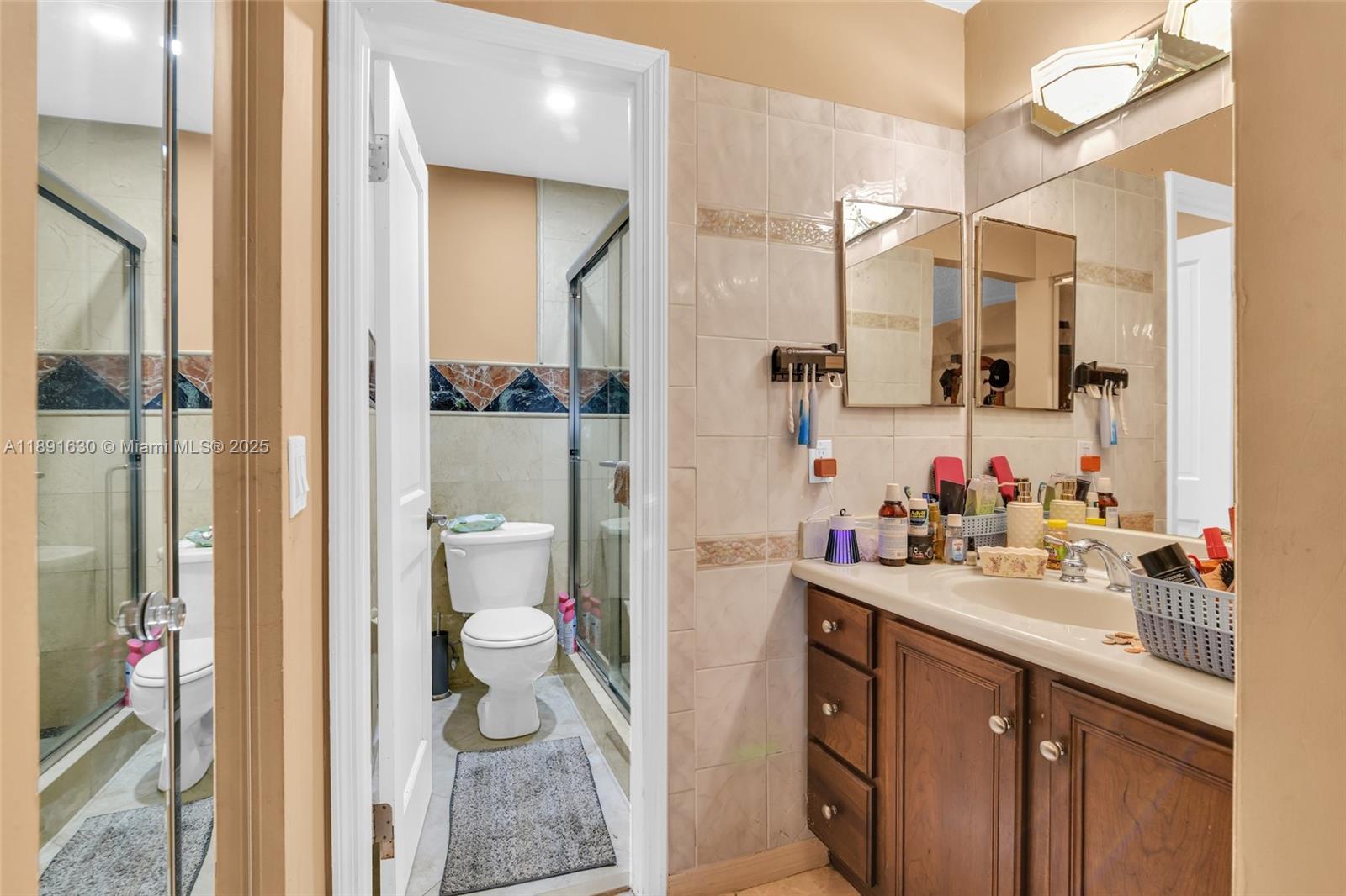 A bathroom features a wooden vanity, a mirror, and a separate toilet and shower area — 13520 SW 116th Ct, Miami FL 33176, MIAMI, FL