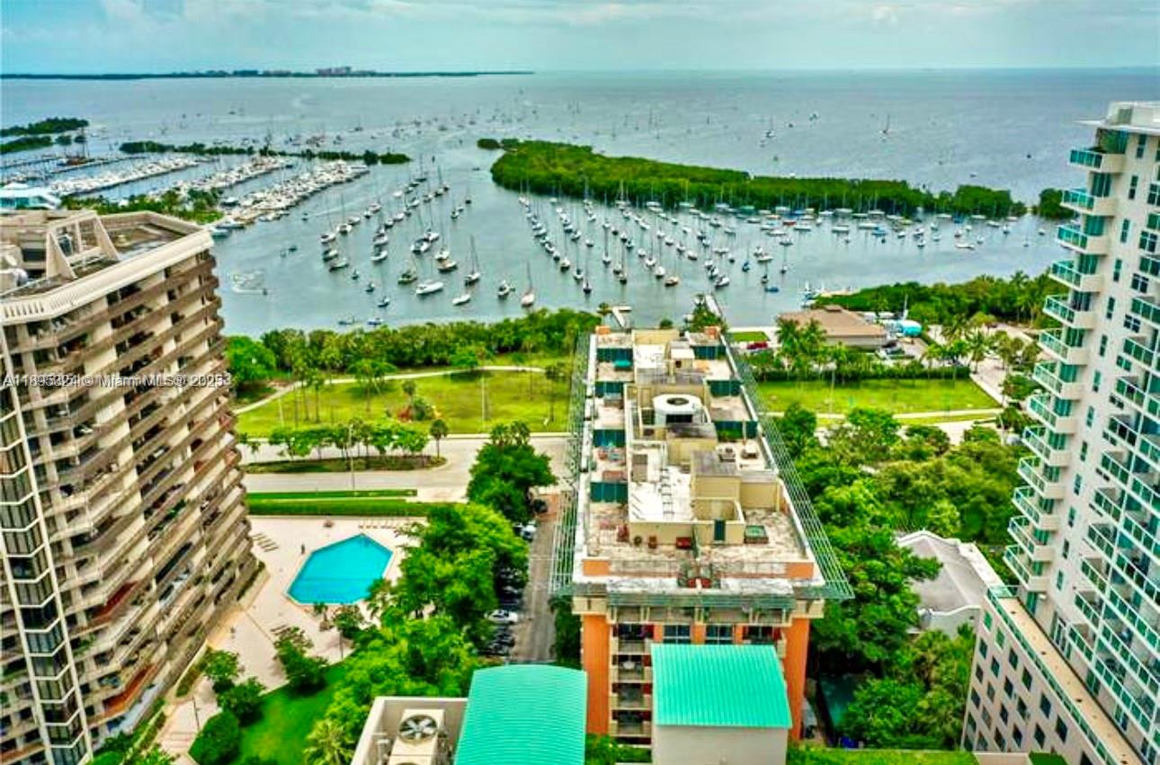 An aerial view shows high-rise buildings, a swimming pool, and a marina filled with boats — 2951 S Bayshore Dr # 603, Miami FL 33133, MIAMI, FL