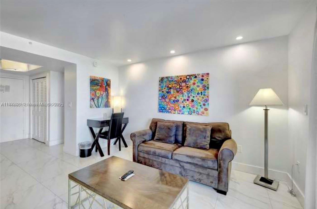 A living room features a brown sofa, a coffee table, and colorful abstract wall art — 2951 S Bayshore Dr # 603, Miami FL 33133, MIAMI, FL