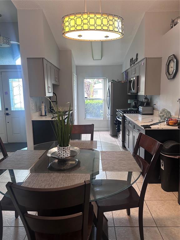 A dining area with a glass table sits adjacent to a kitchen with dark cabinetry — 2527 10TH AVENUE S, ST PETERSBURG, FL
