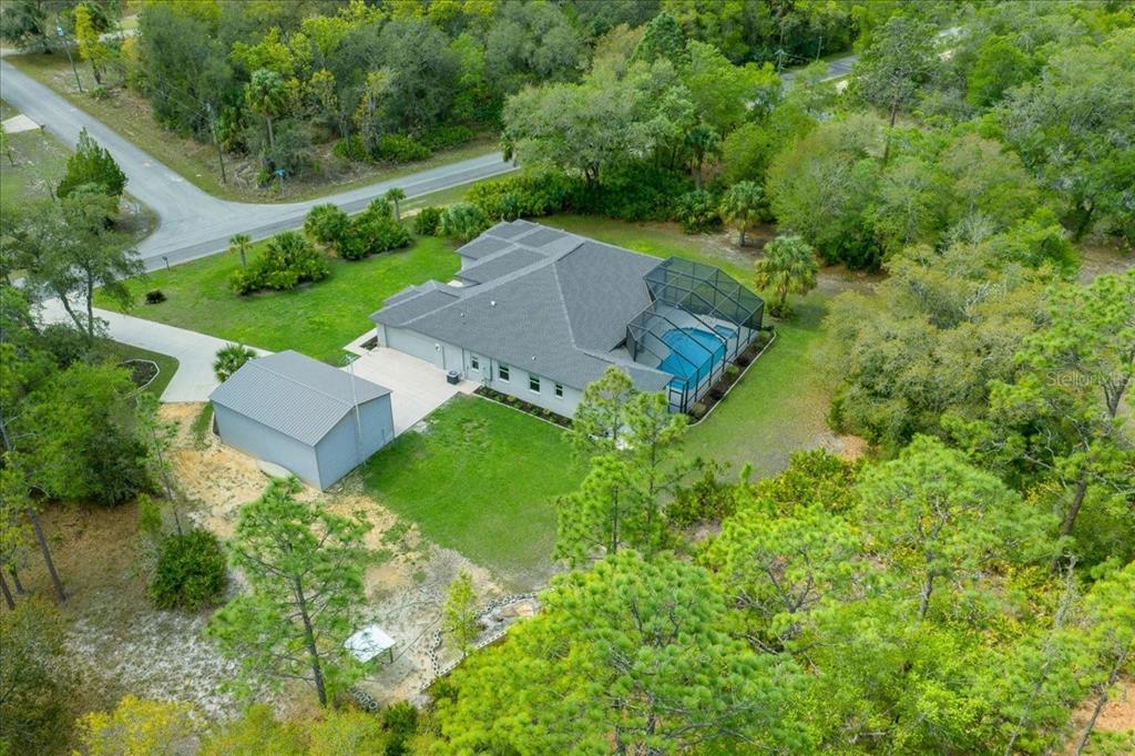 An aerial view shows a house with a pool enclosure, detached garage, and surrounding woods — 11667 W BLUEBELL DRIVE, CRYSTAL RIVER, FL