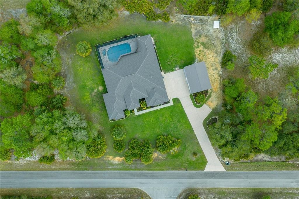 An aerial view shows a house with a pool, detached garage, and driveway on a lot — 11667 W BLUEBELL DRIVE, CRYSTAL RIVER, FL