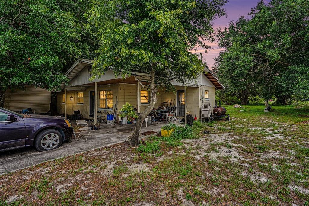 A single-story house with a concrete porch, a parked car, and surrounding trees — 607 2ND AVENUE, LAKE WALES, FL