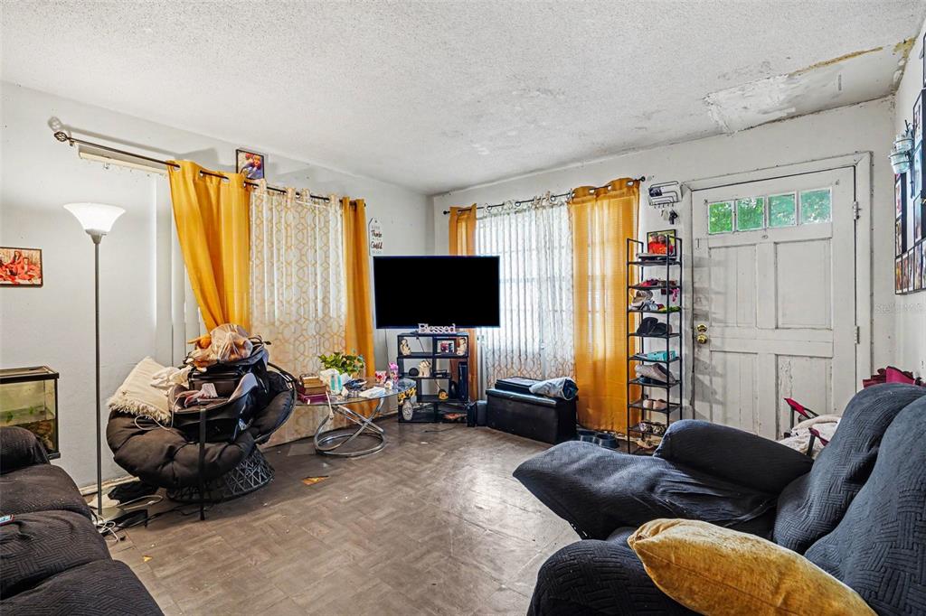 A living room features dark furniture, yellow curtains, a television, and a white front door — 607 2ND AVENUE, LAKE WALES, FL
