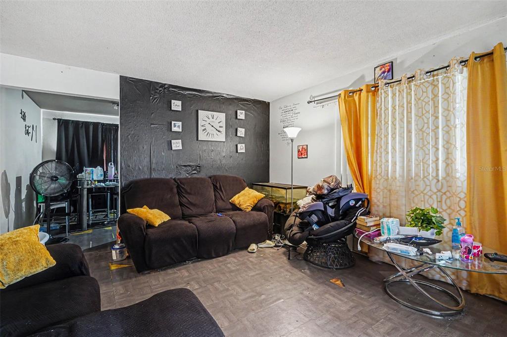 A living room features a dark accent wall, brown sofa, and yellow curtains — 607 2ND AVENUE, LAKE WALES, FL