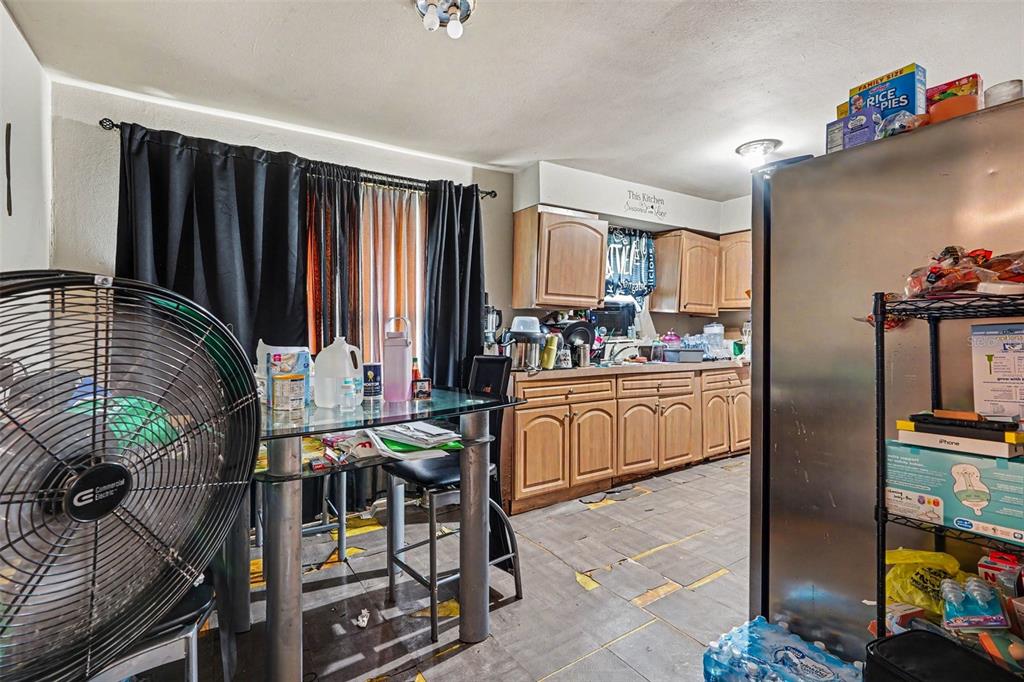 A kitchen features wood cabinets, a glass-top dining table, and a large floor fan — 607 2ND AVENUE, LAKE WALES, FL